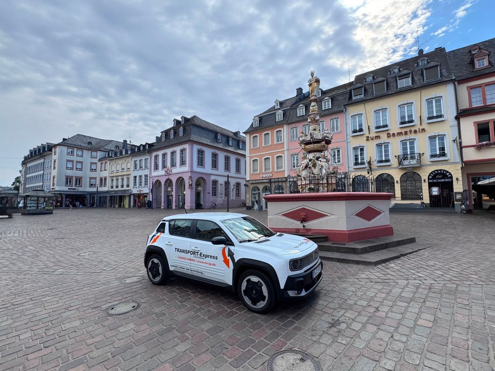 Weißes Transport-Express-Fahrzeug auf dem Trierer Hauptmarkt vor dem Petrusbrunnen